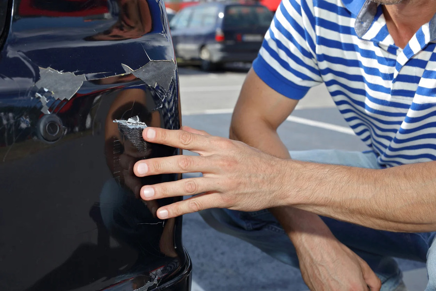 a guy checking the front left bumper for scratches and dents. One of the important things to check before renting a car.
